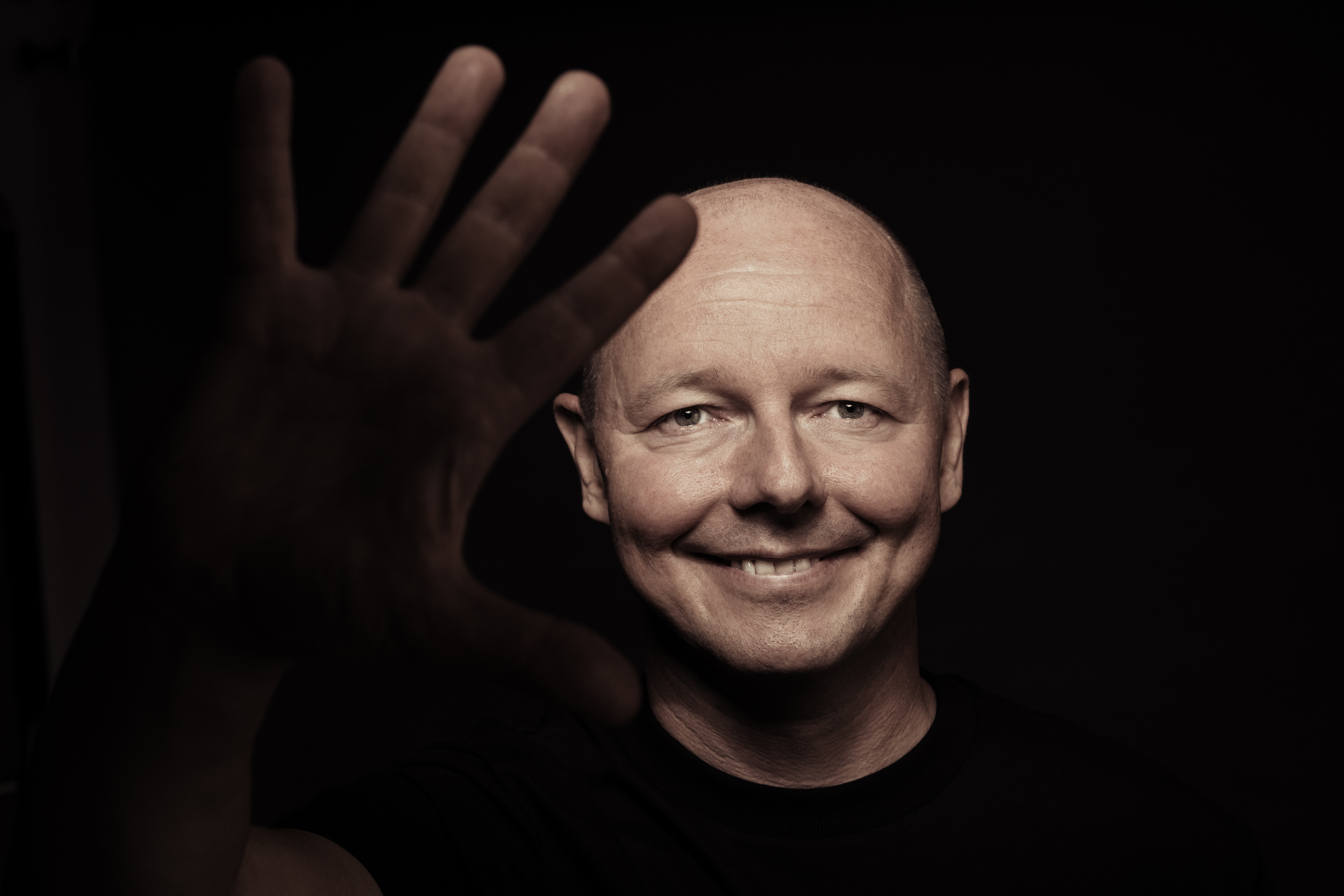 Jan Buschmeyer smiling, with an open hand reaching towards the camera